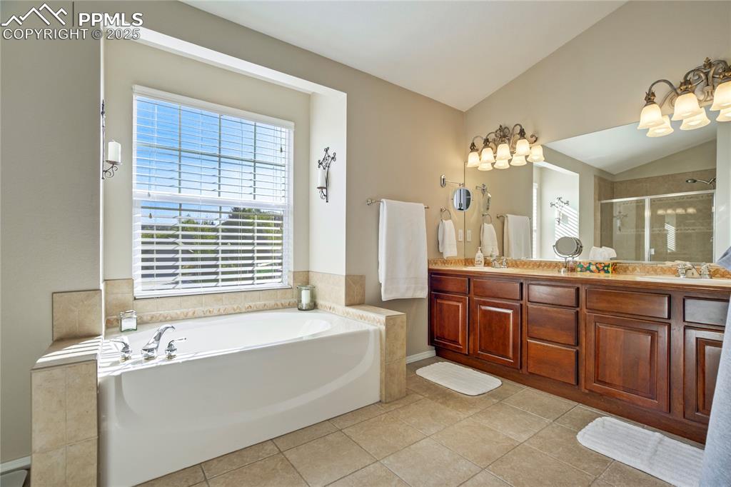 Image 20 of 43: Bathroom with a garden tub, vaulted ceiling, a shower stall, light tile pat