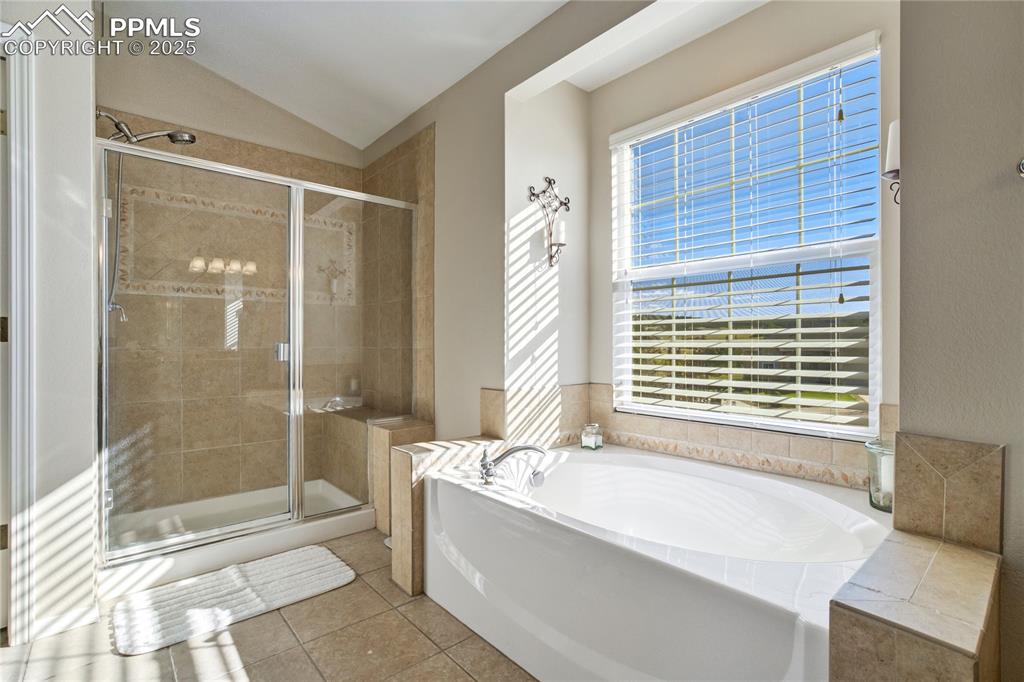 Image 21 of 43: Bathroom with a bath, a stall shower, vaulted ceiling, and tile patterned f