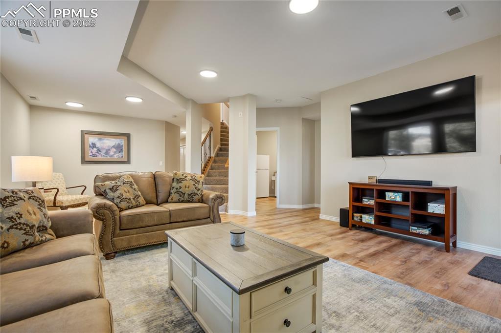 Image 29 of 43: Living area with light wood-style floors, stairs, and recessed lighting