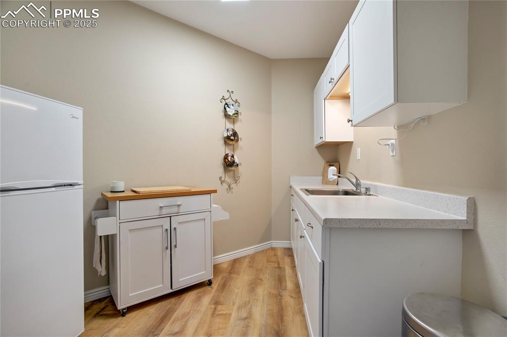 Image 31 of 43: Kitchen with freestanding refrigerator, light wood-style floors, light coun