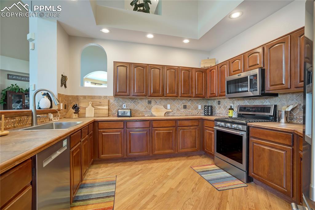 Image 7 of 43: Kitchen featuring appliances with stainless steel finishes, brown cabinets,