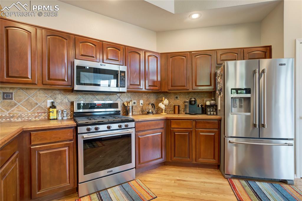 Image 8 of 43: Kitchen with appliances with stainless steel finishes, light countertops, l