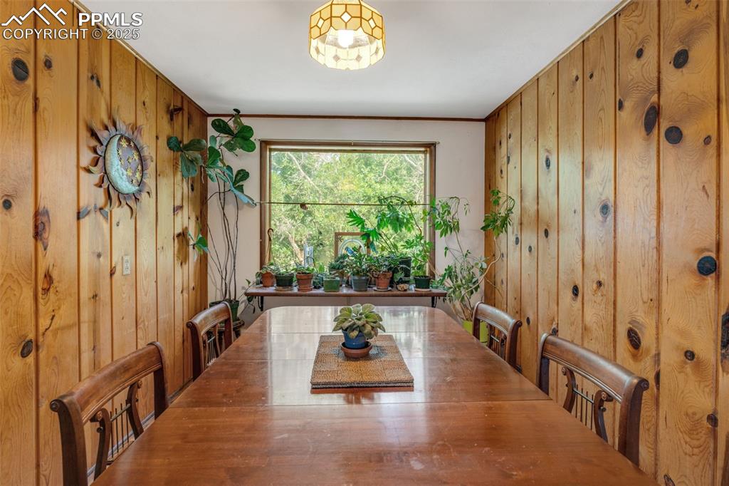 Image 10 of 50: Dining room with wood paneled walls and large window letting in natural lig