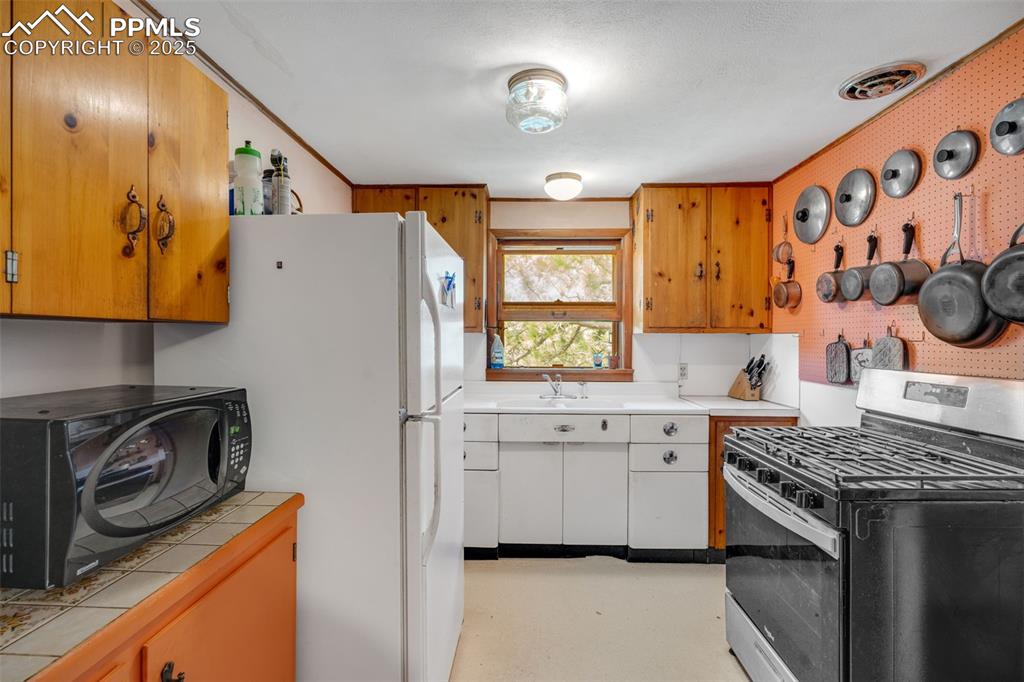 Image 12 of 50: Charming kitchen with stainless steel gas cooktop and oven, cast iron sink