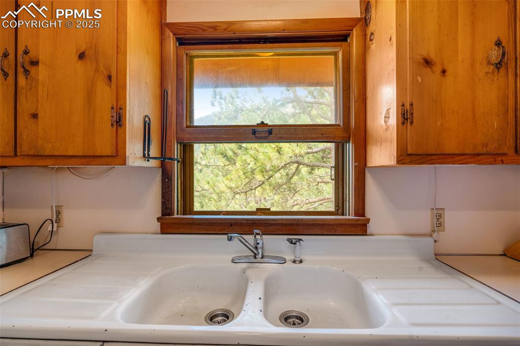 Image 13 of 50: Window in kitchen outlooking onto treed lot and mountain