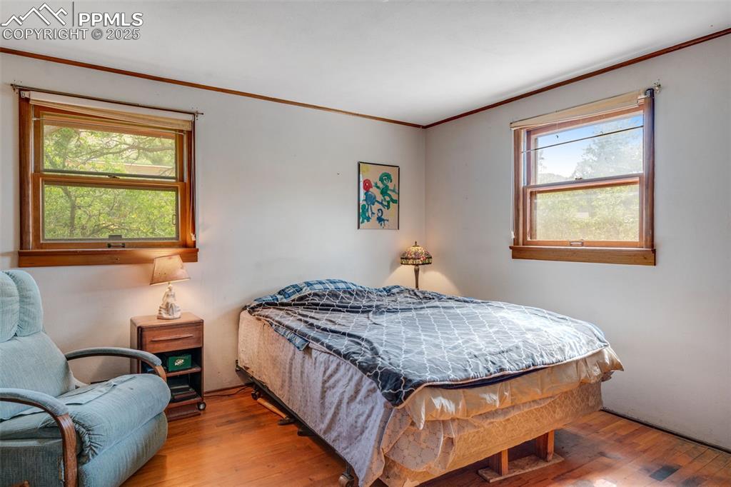 Image 20 of 50: Bedroom featuring original wood flooring, ornamental molding and 2 windows