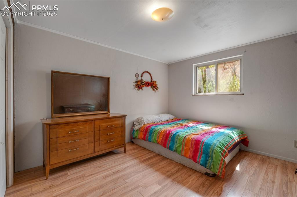 Image 32 of 50: Bedroom featuring light wood-style floors and ornamental molding