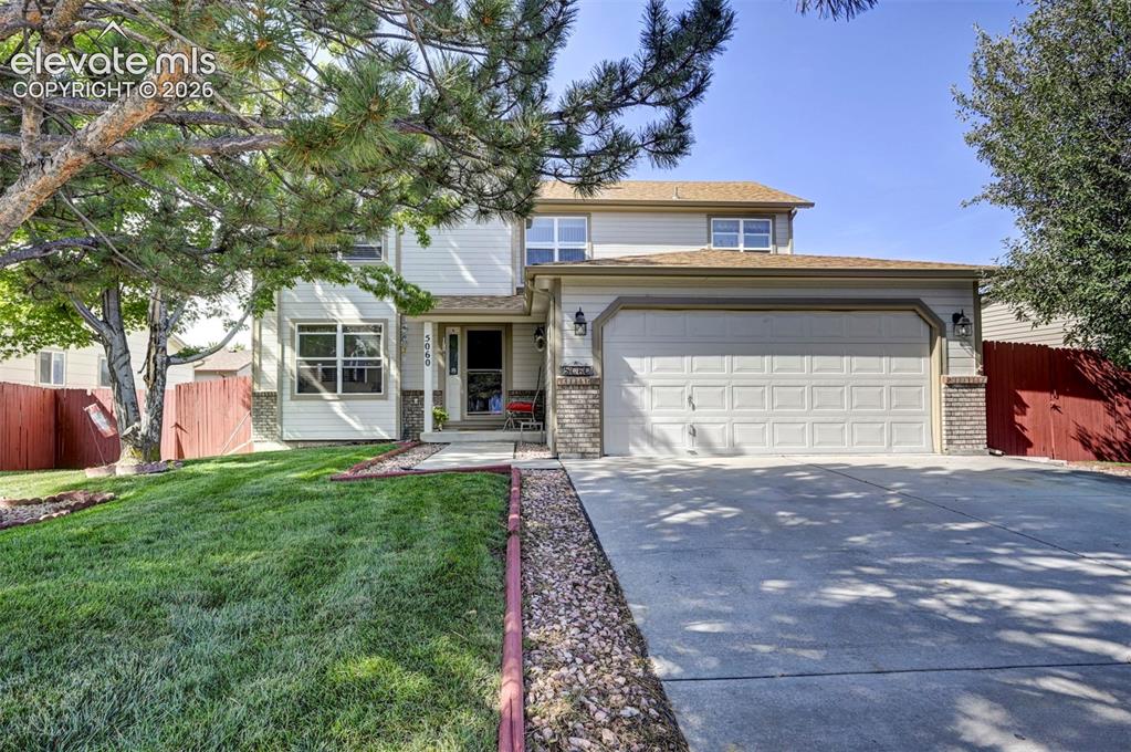Caption: Front view of home and front yard with mature trees and beautiful lawn.