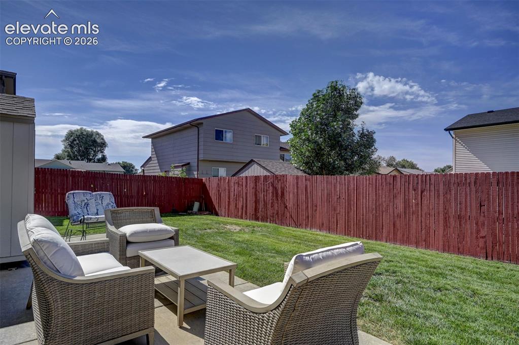 Image 47 of 50: Seating area in the backyard with large cement patio.