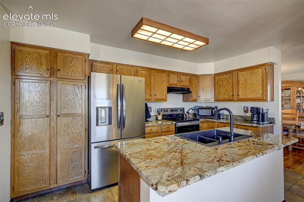 Image 7 of 50: Kitchen island with granite countertop plus granite backsplash.