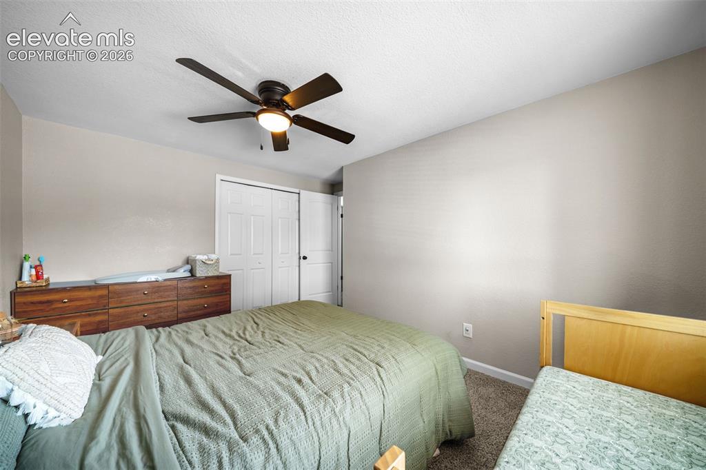 Image 16 of 39: Bedroom featuring a ceiling fan, neutral wall paint, and textured carpeting