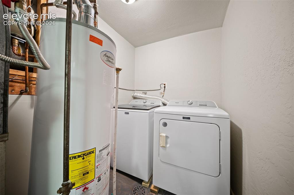 Image 29 of 39: Dedicated utility area featuring a water heater and laundry appliances