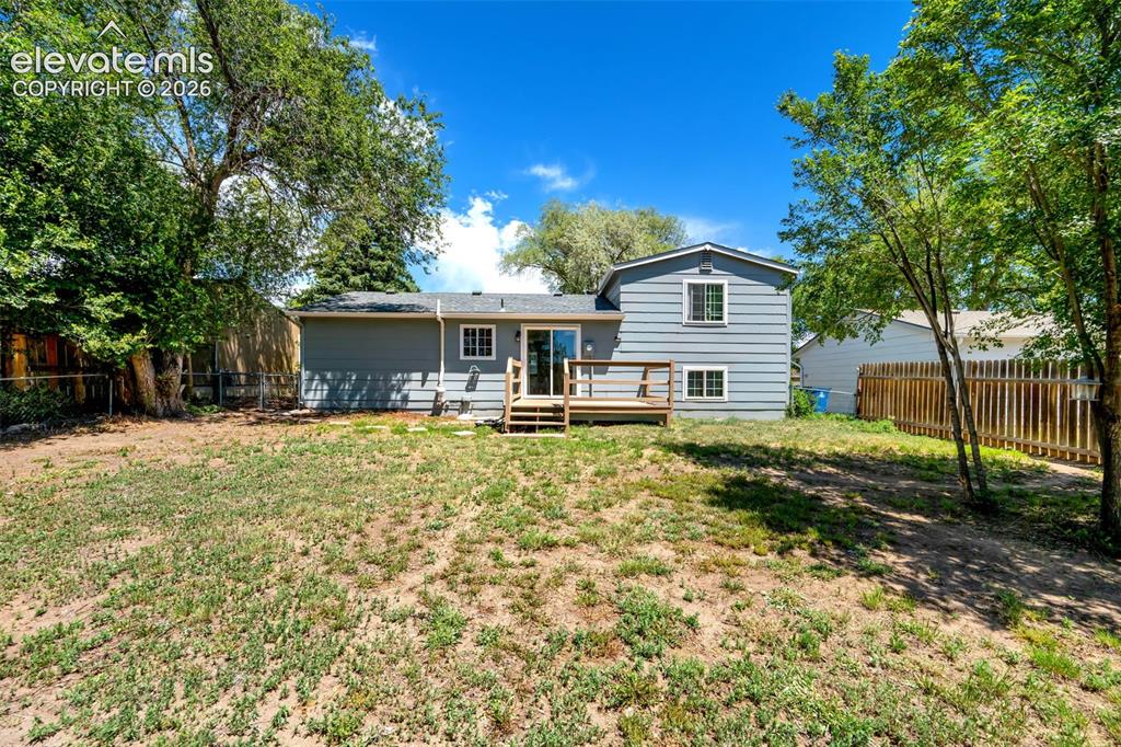 Image 34 of 39: Expansive backyard featuring a natural landscape, mature trees, wood privac