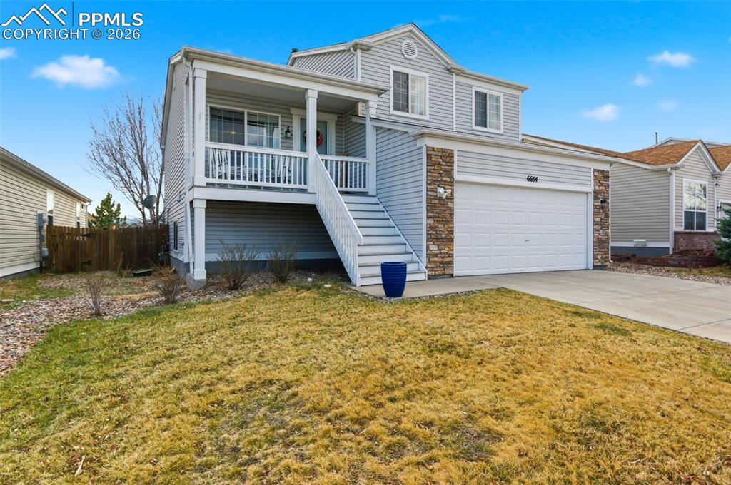 Caption: View of front of property featuring driveway, covered porch, and stone siding