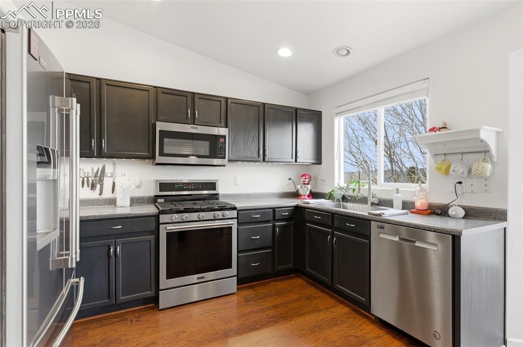 Image 11 of 44: Kitchen with stainless steel appliances, vaulted ceiling, dark wood-style f