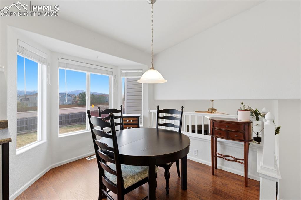 Image 14 of 44: Dining space with wood finished floors, lofted ceiling, and a mountain view