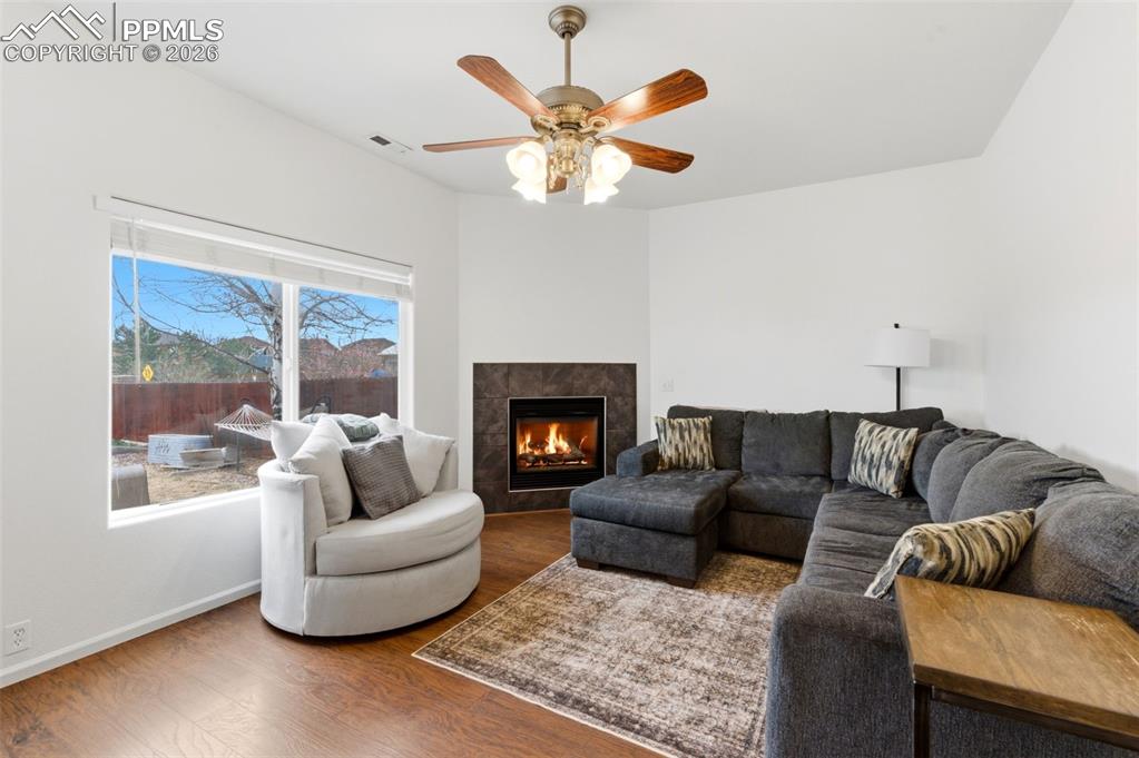 Image 16 of 44: Living room with a fireplace, wood finished floors, and ceiling fan