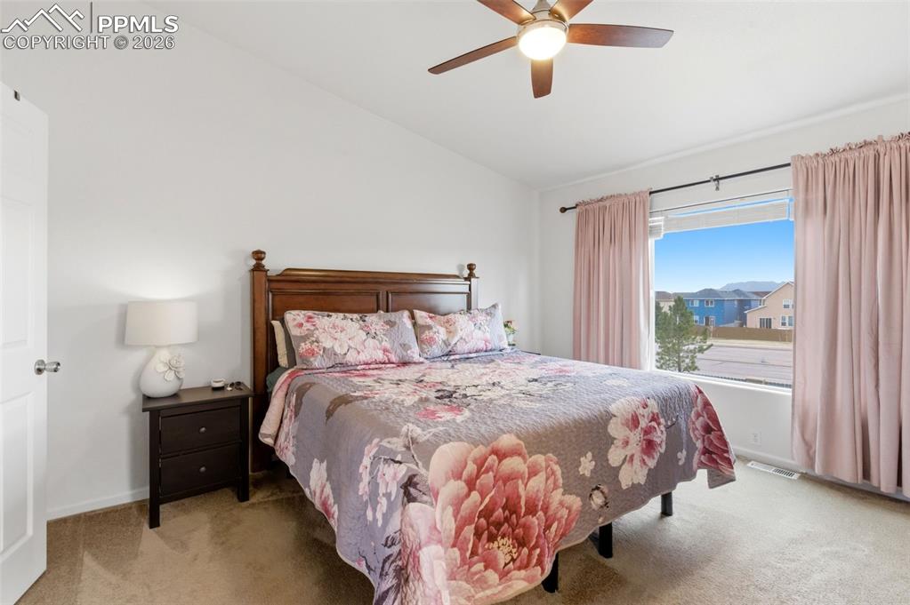 Image 21 of 44: Bedroom with vaulted ceiling, light carpet, and a ceiling fan