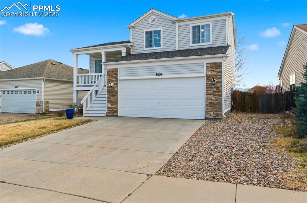 Image 3 of 44: View of front of property with driveway, stone siding, and a garage