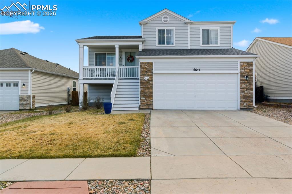 Image 4 of 44: View of front of home featuring stone siding, concrete driveway, covered po