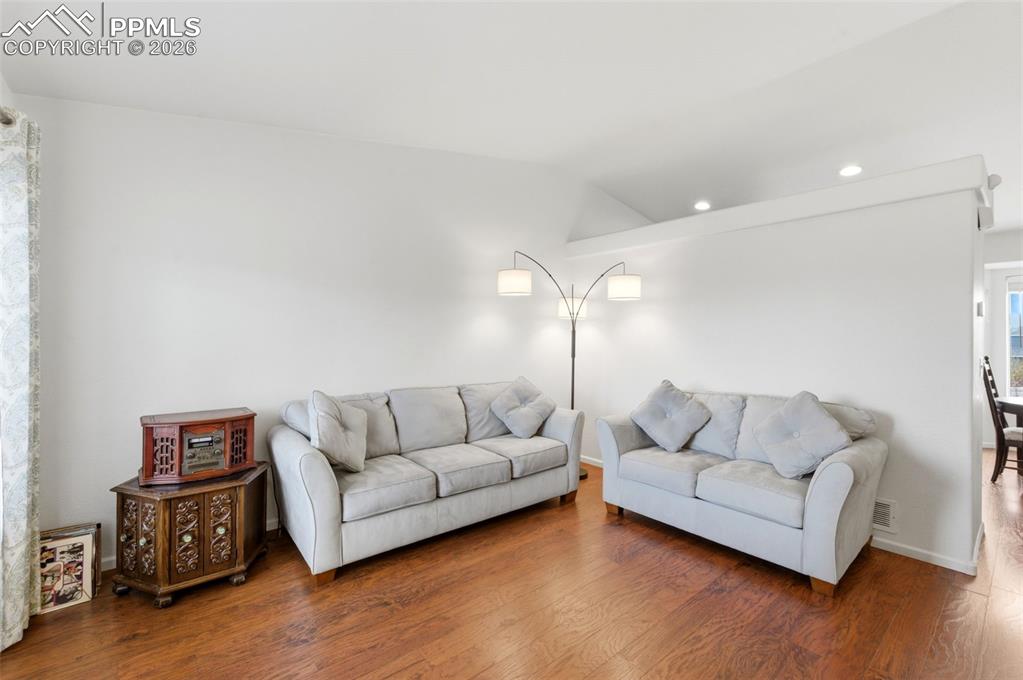 Image 8 of 44: Living room featuring vaulted ceiling, wood finished floors, and recessed l