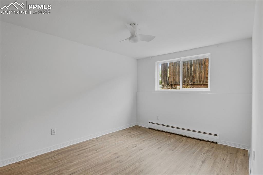 Image 11 of 17: Unfurnished room featuring baseboard heating, light wood finished floors, a