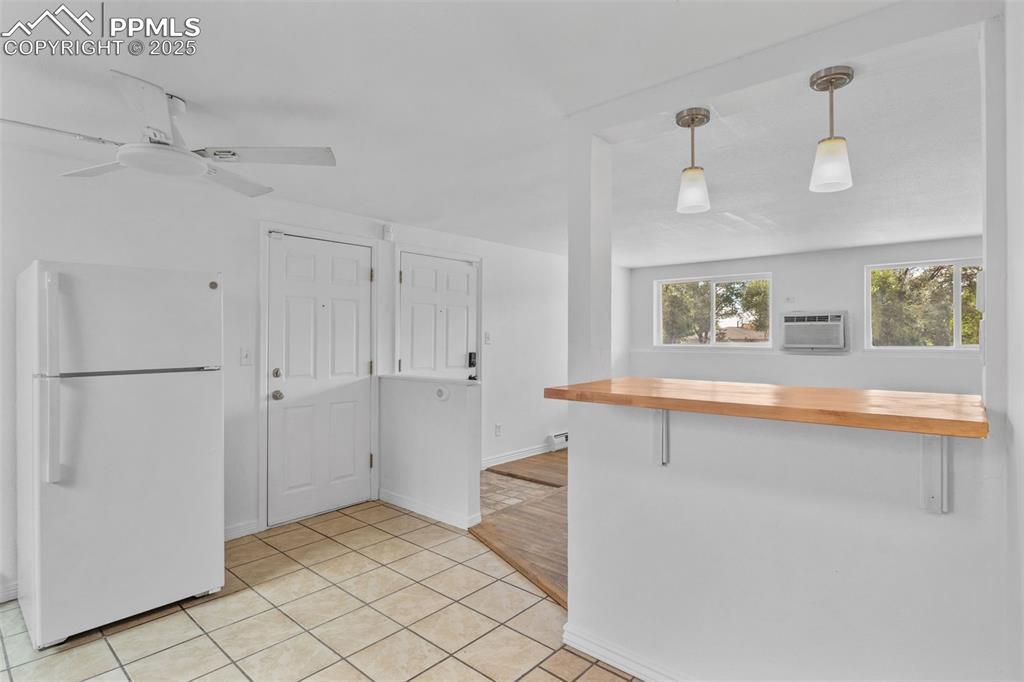 Image 8 of 17: Kitchen with wooden counters, freestanding refrigerator, pendant lighting,