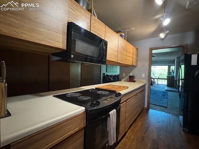 Image 15 of 17: Kitchen featuring black appliances, dark wood-style flooring, light counter