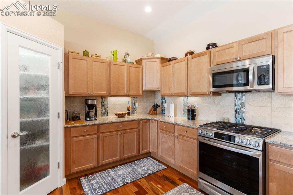 Image 11 of 33: Kitchen with appliances with stainless steel finishes, vaulted ceiling, tas