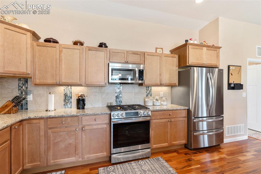 Image 12 of 33: Kitchen with stainless steel appliances, light wood-style flooring, decorat