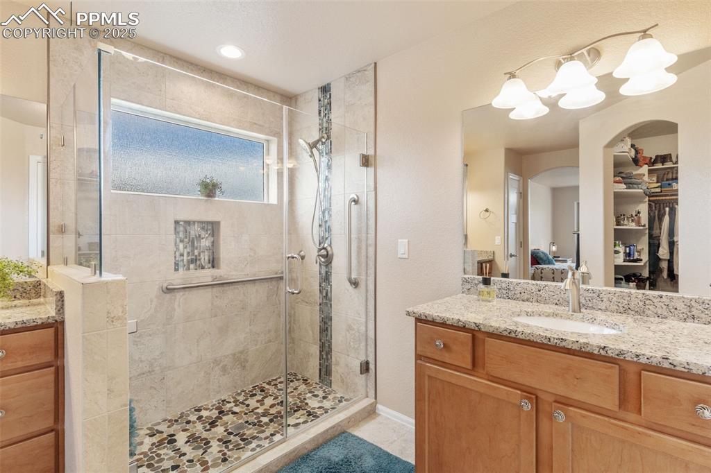 Image 18 of 33: Bathroom featuring a shower stall, vanity, tile patterned floors, and a cha