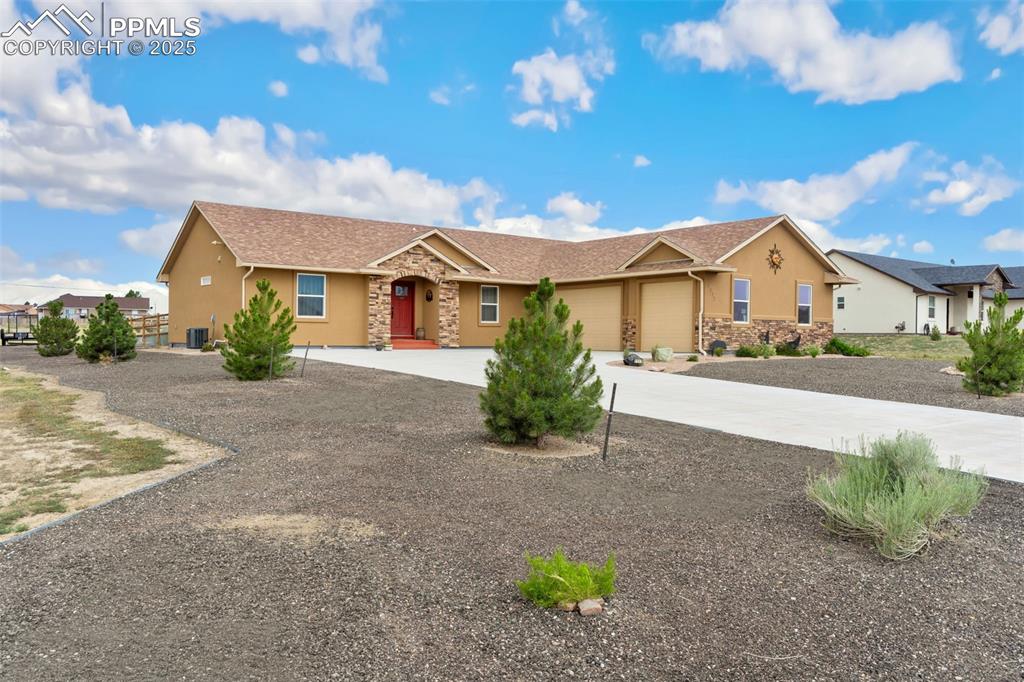 Image 2 of 33: Ranch-style home with stone siding, stucco siding, an attached garage, and