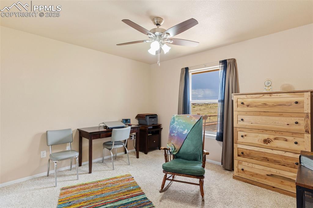Image 22 of 33: Living area with a ceiling fan, a desk, and light carpet