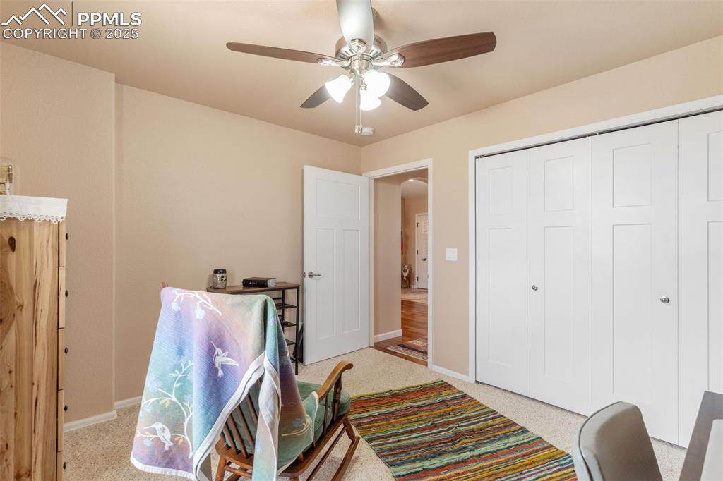 Image 23 of 33: Home office with ceiling fan and light carpet