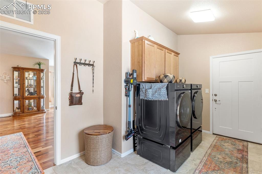 Image 25 of 33: Washroom with cabinet space, washing machine and dryer, and light wood-type