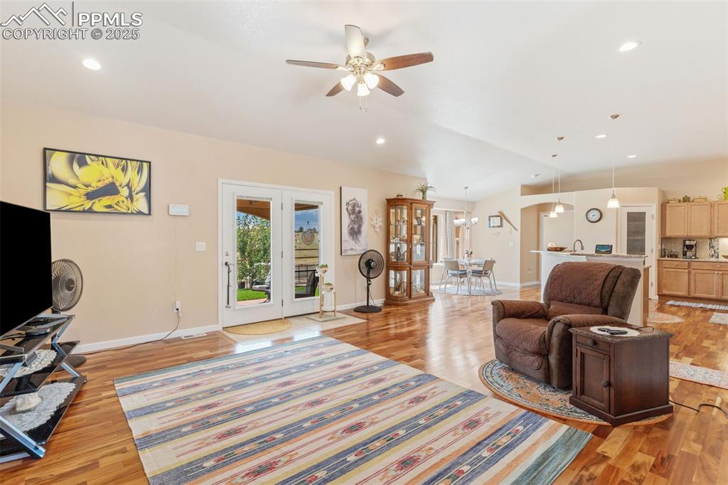 Image 7 of 33: Living area with light wood finished floors, a ceiling fan, recessed lighti