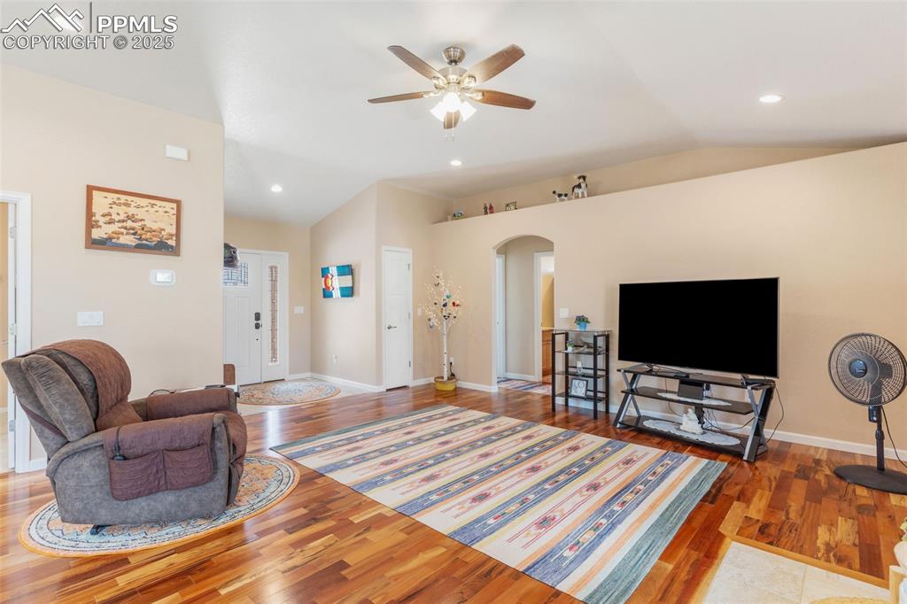 Image 9 of 33: Living room featuring lofted ceiling, arched walkways, wood finished floors
