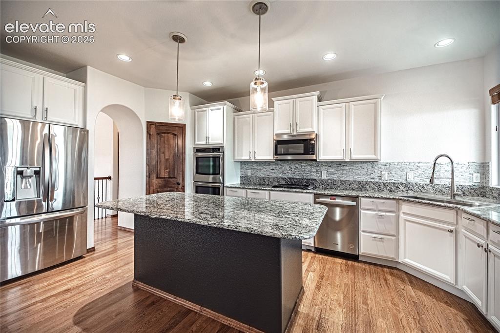 Image 12 of 48: Kitchen featuring a central island with a stone countertop, stainless steel
