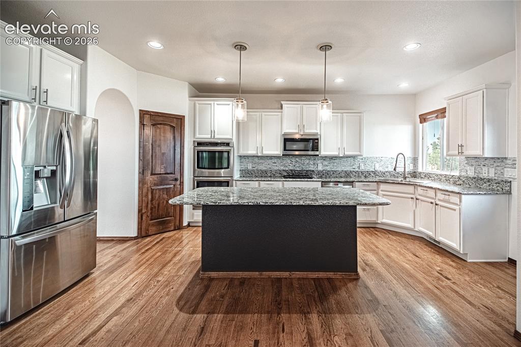 Image 13 of 38: Kitchen featuring a large central island with a contrasting base, wood-fini