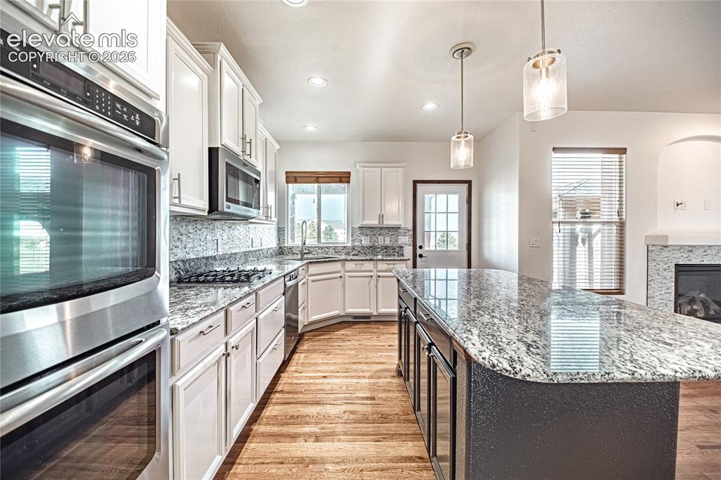 Image 16 of 38: Spacious kitchen with a large central island featuring a stone countertop,