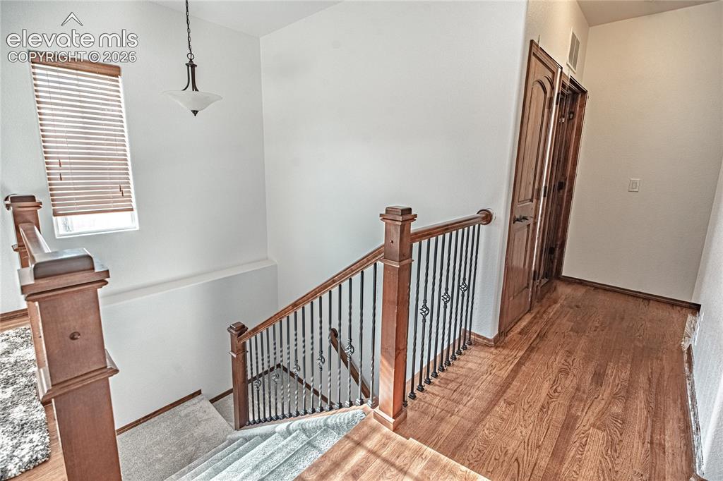 Image 17 of 38: Staircase featuring wood newel posts, wrought iron balusters, and carpeted