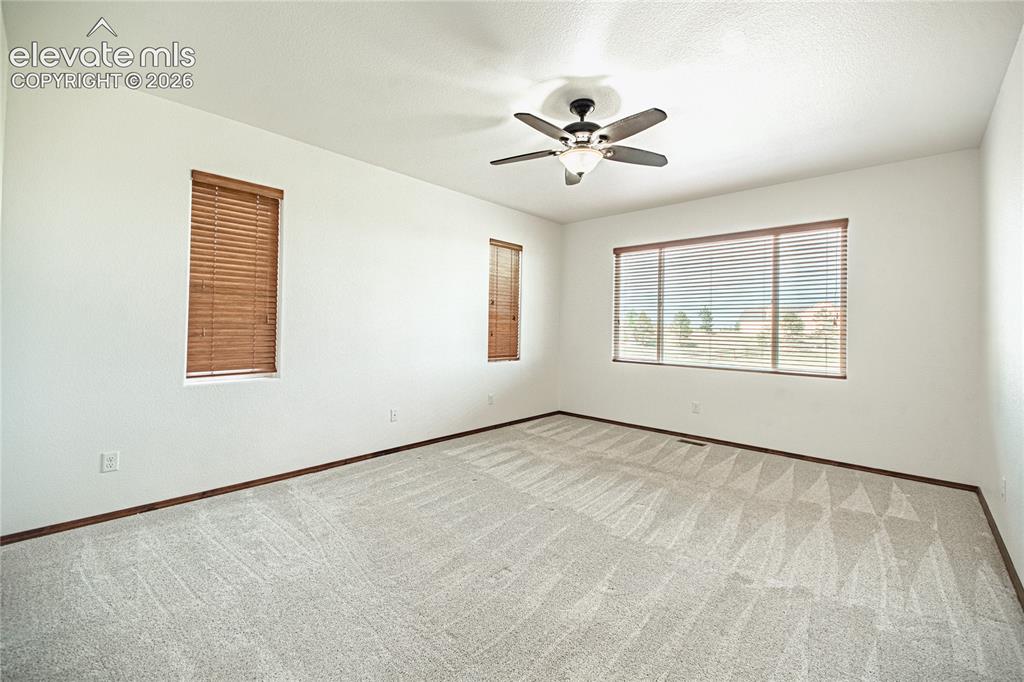 Image 18 of 38: Spacious room featuring light-colored patterned carpeting, white walls, and