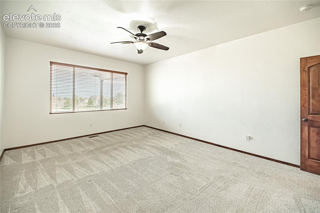Image 21 of 38: Spacious room featuring light-colored carpet, a large window with horizonta