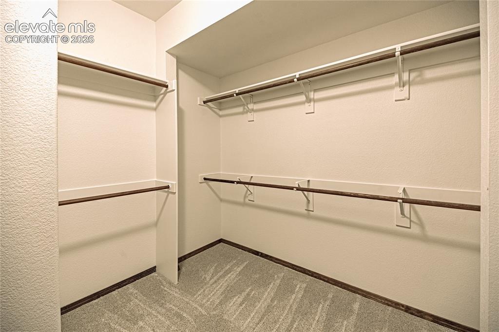 Image 26 of 38: Walk-in closet featuring white painted walls, multi-level hanging rods, bui