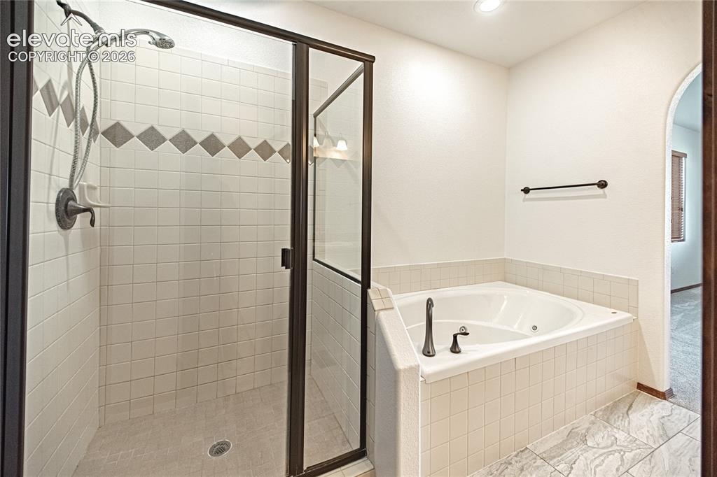 Image 27 of 48: Spacious bathroom featuring a glass-enclosed shower with tiled walls and a