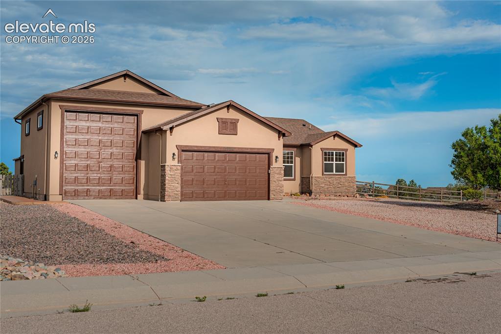 Image 3 of 38: Contemporary stucco exterior with a multi-car garage, stone accents, and a