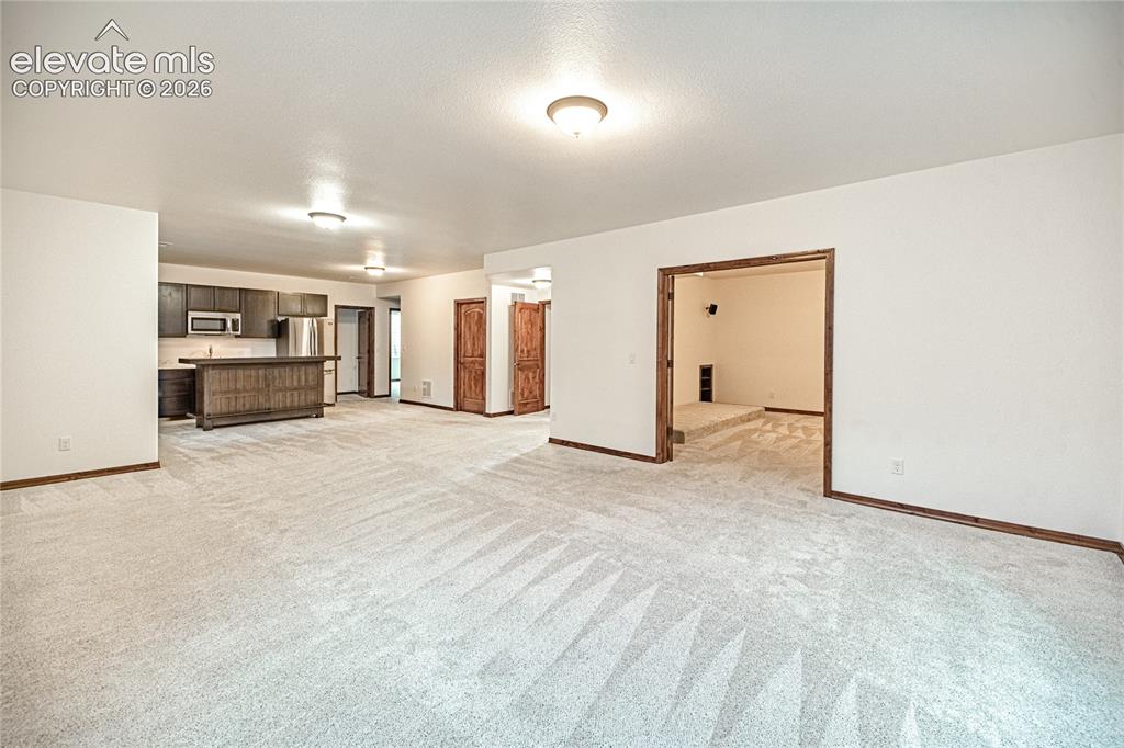 Image 31 of 48: Spacious interior featuring light-toned carpeting and white walls with wood