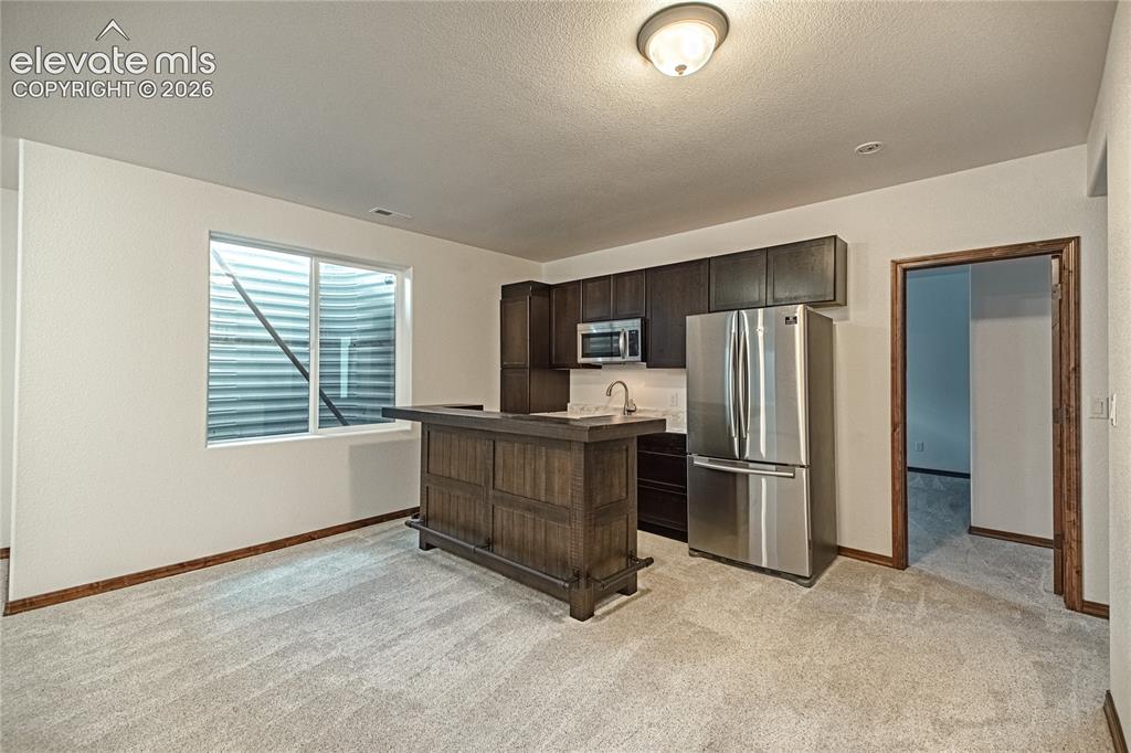 Image 34 of 48: Lower-level recreation space featuring new carpeting, a built-in wet bar wi