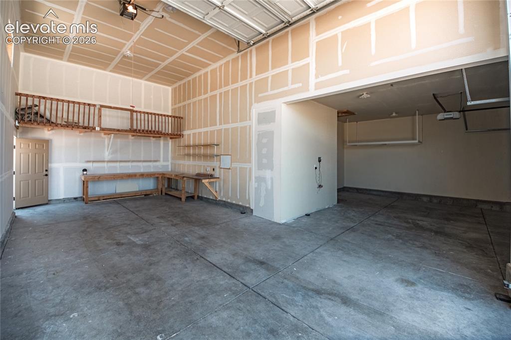 Image 39 of 48: Spacious garage featuring a concrete floor, high ceilings, and an overhead