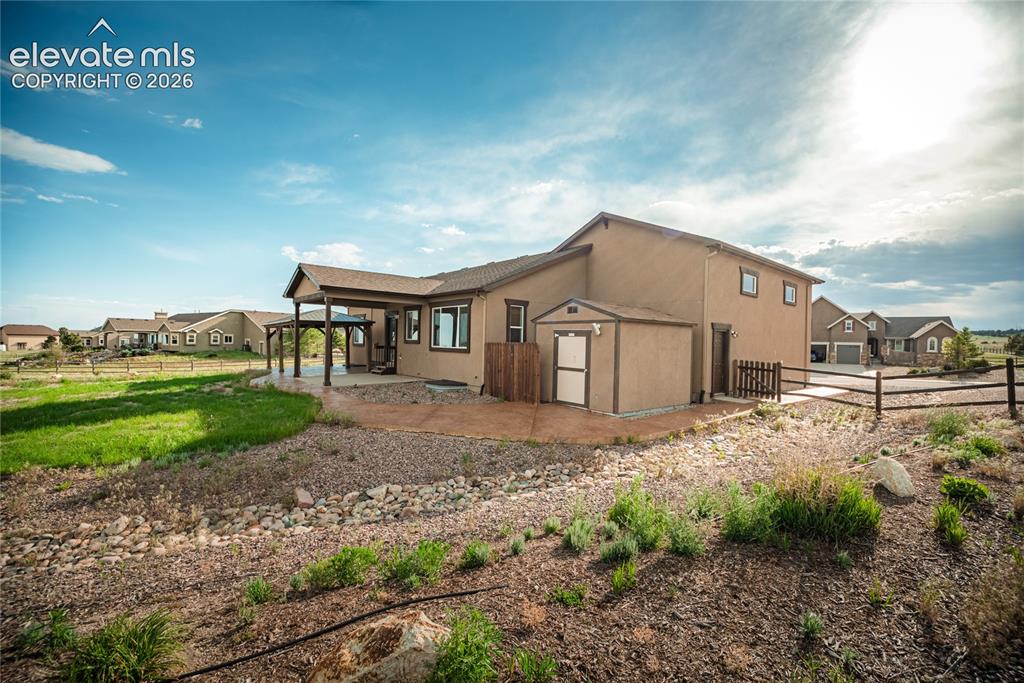 Image 42 of 48: Stucco exterior with a covered patio, a detached storage shed, a fenced sid